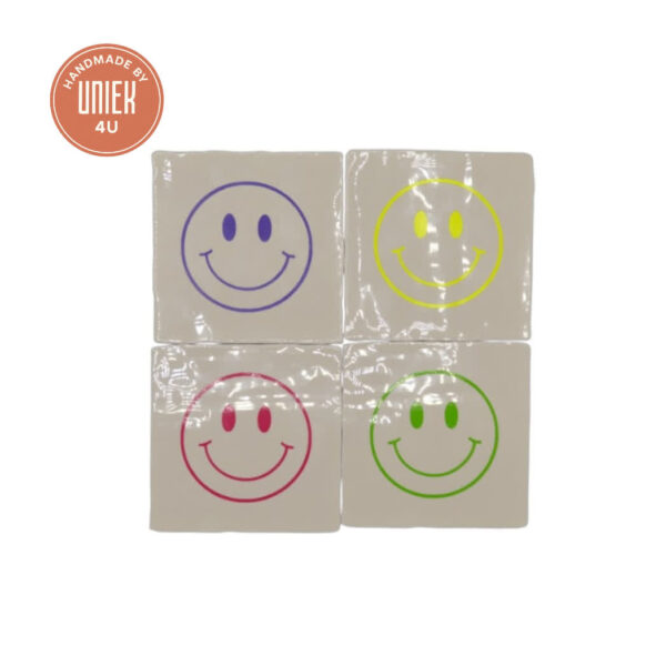 Tegeltje Smileys handgemaakt keramiek 10x10 cm in diverse kleuren – roze, geel, paars en groen, speels op plank geplaatst