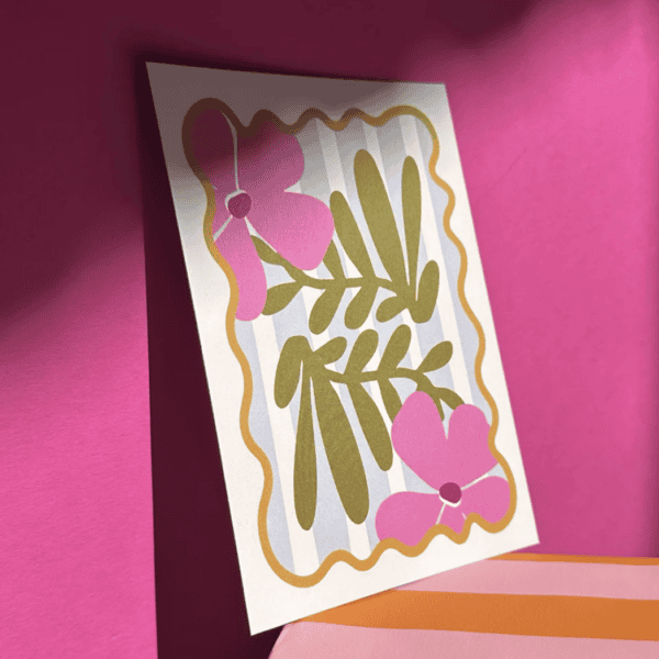 Vrolijk gekleurde bloemen en blaadjes poster op roze muur.